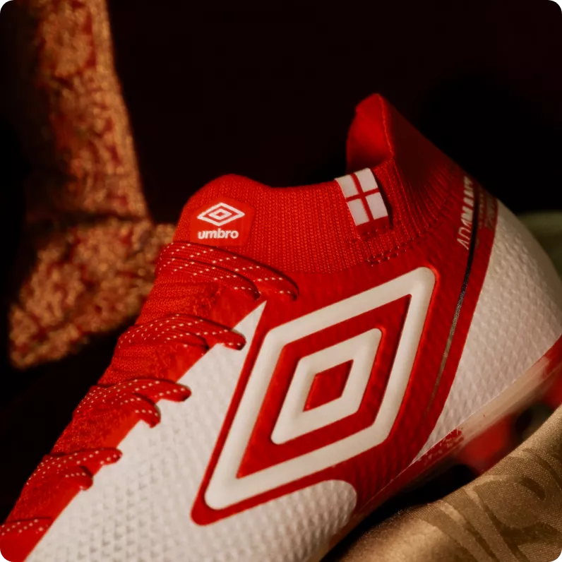 Detalhe da bandeira da Inglaterra no calcanhar da chuteira Umbro vermelha e branca