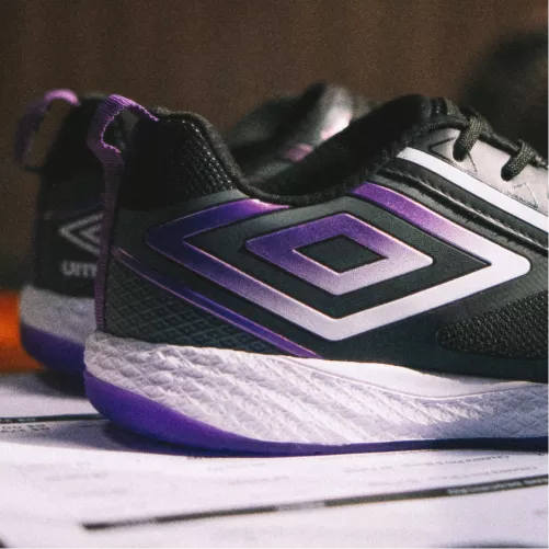 Detalhe do logo roxo na lateral da chuteira futsal Umbro preta